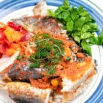 baked whole catfish on a white and blue plate