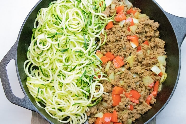 overhead view of a cast iron skillet with Zucchini and Ground Beef Stir Fry including lots of fresh zoodles.