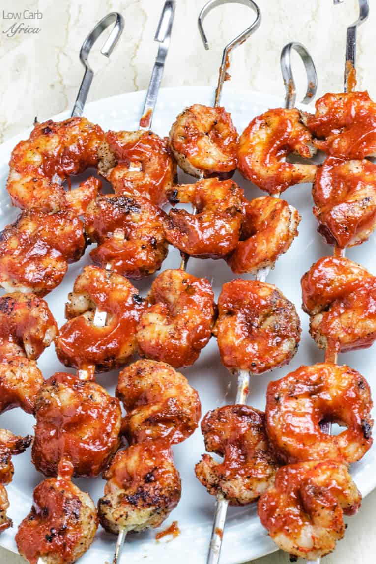Shrimp and barbecue sauce on metal skewers.