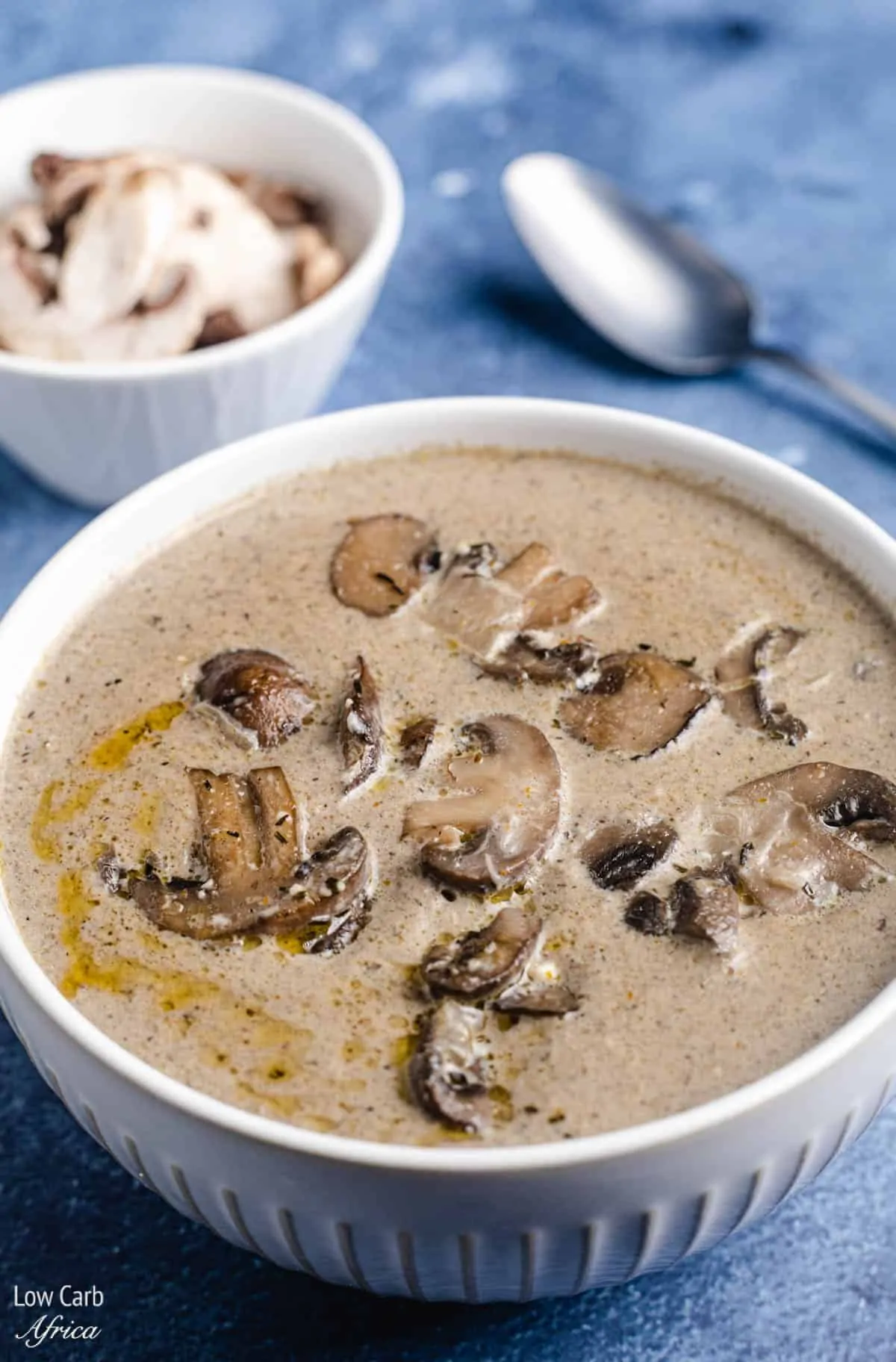 A bowl of keto mushroom soup with a spoon on the side