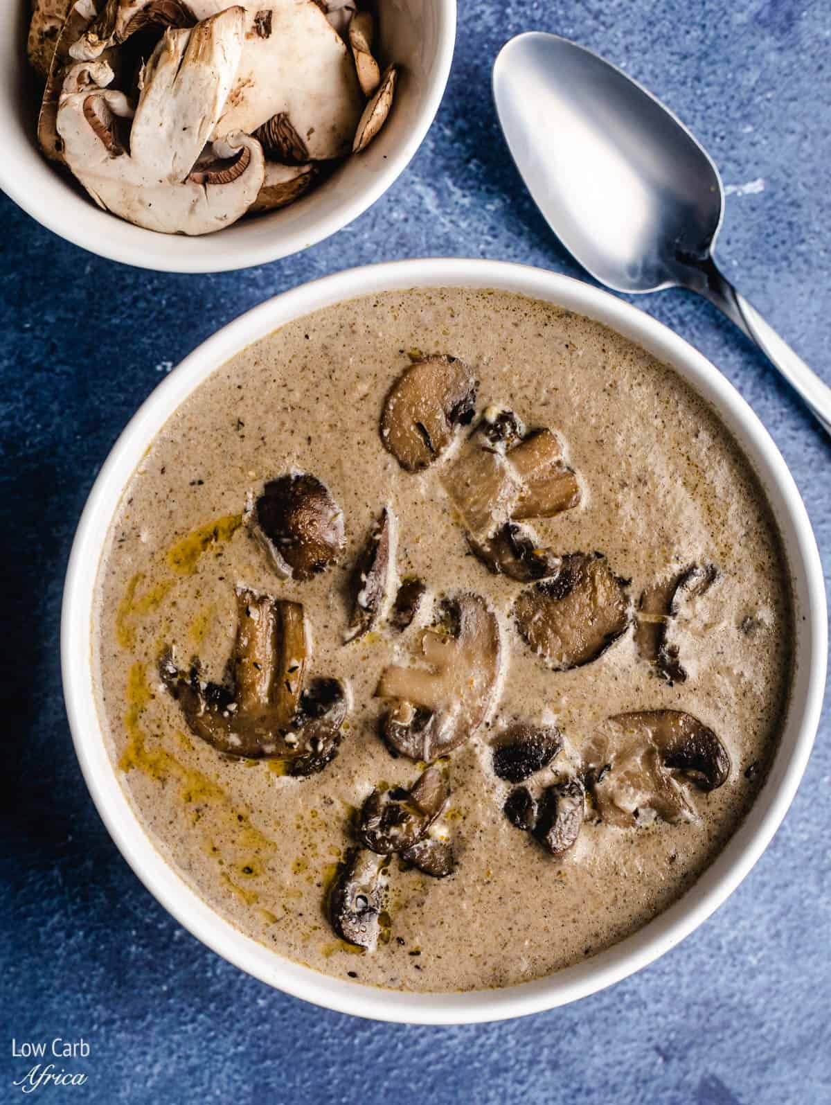 A bowl of keto mushroom soup with a spoon on the side