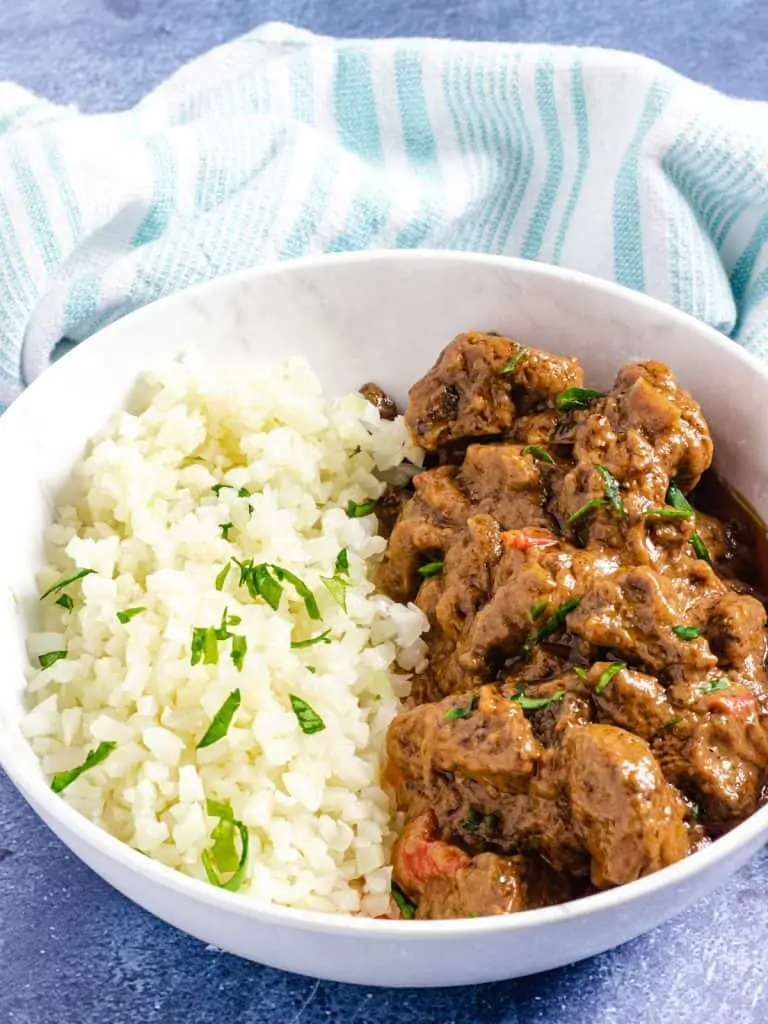 peanut stew in a white bowl with cauliflower rice