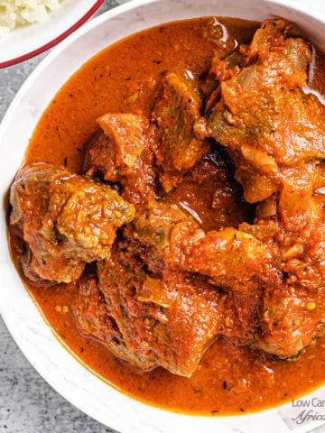 close up image of goat stew in tomato sauce