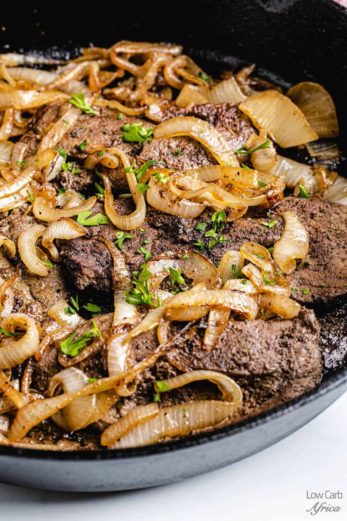 liver and onions closeup in a cast iron skillet.