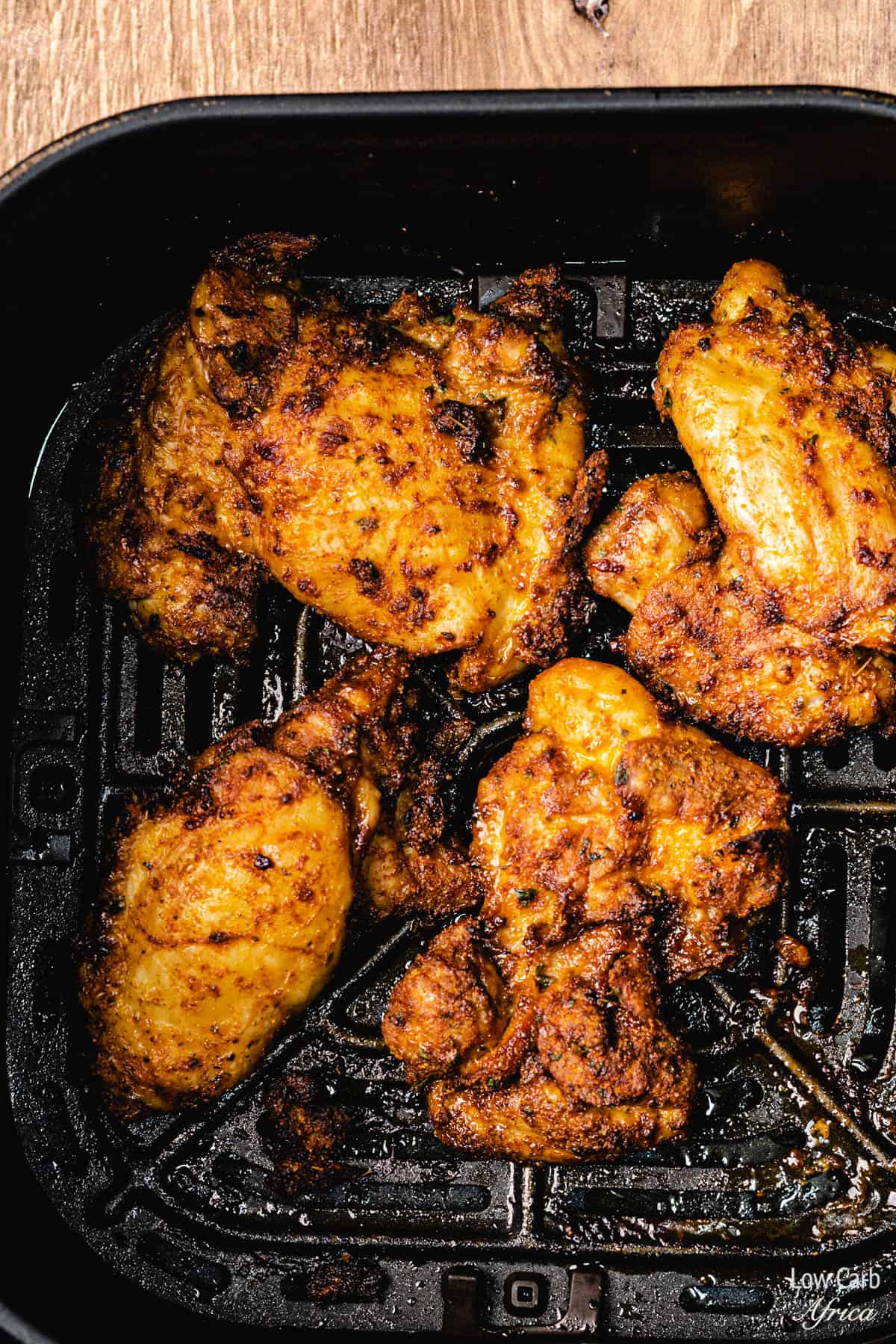 Boneless chicken thighs in an air fryer pan.