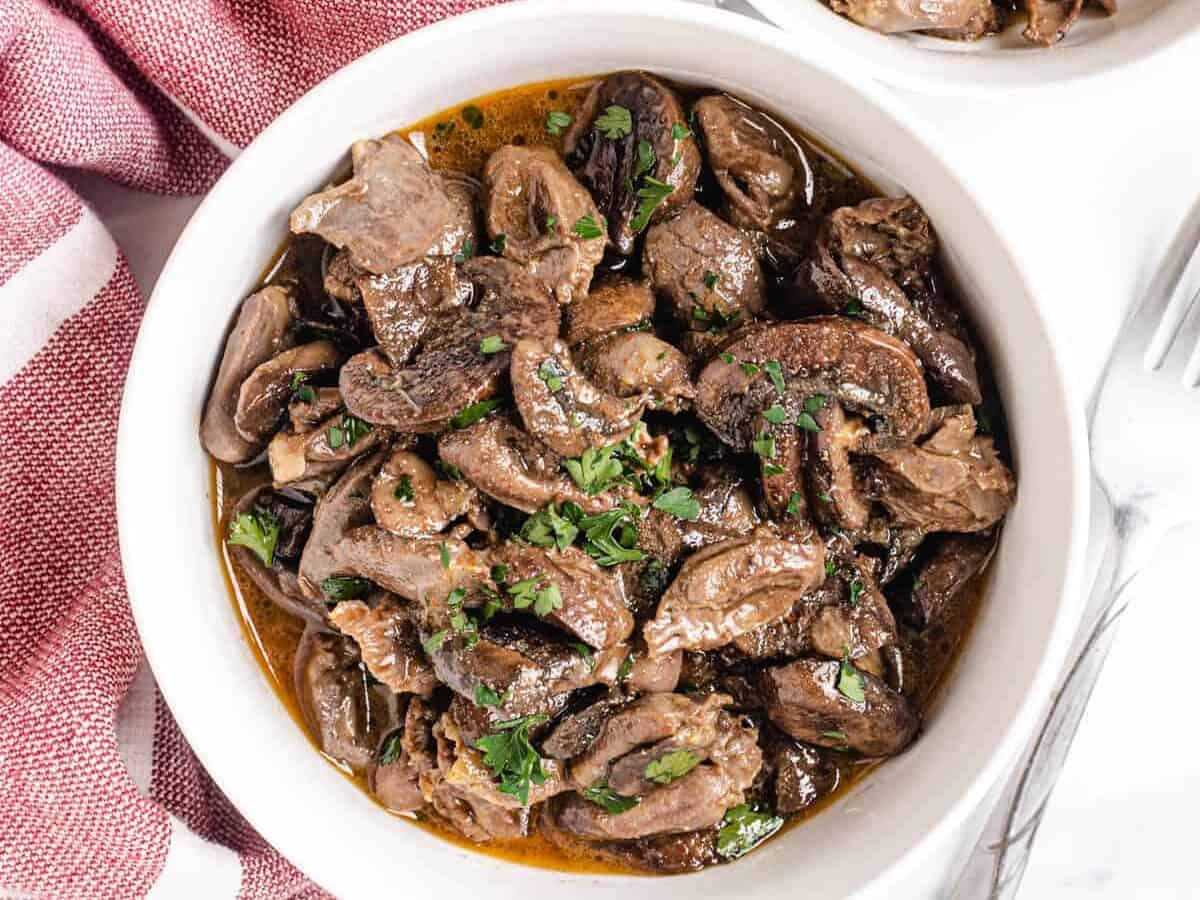 white bowl of chicken hearts with mushrooms.