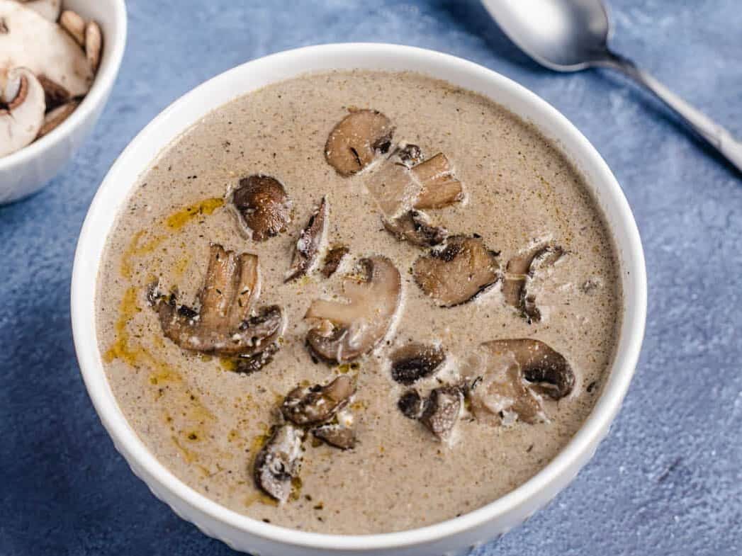 a wide image showing a bowl of soup with mushrooms on top