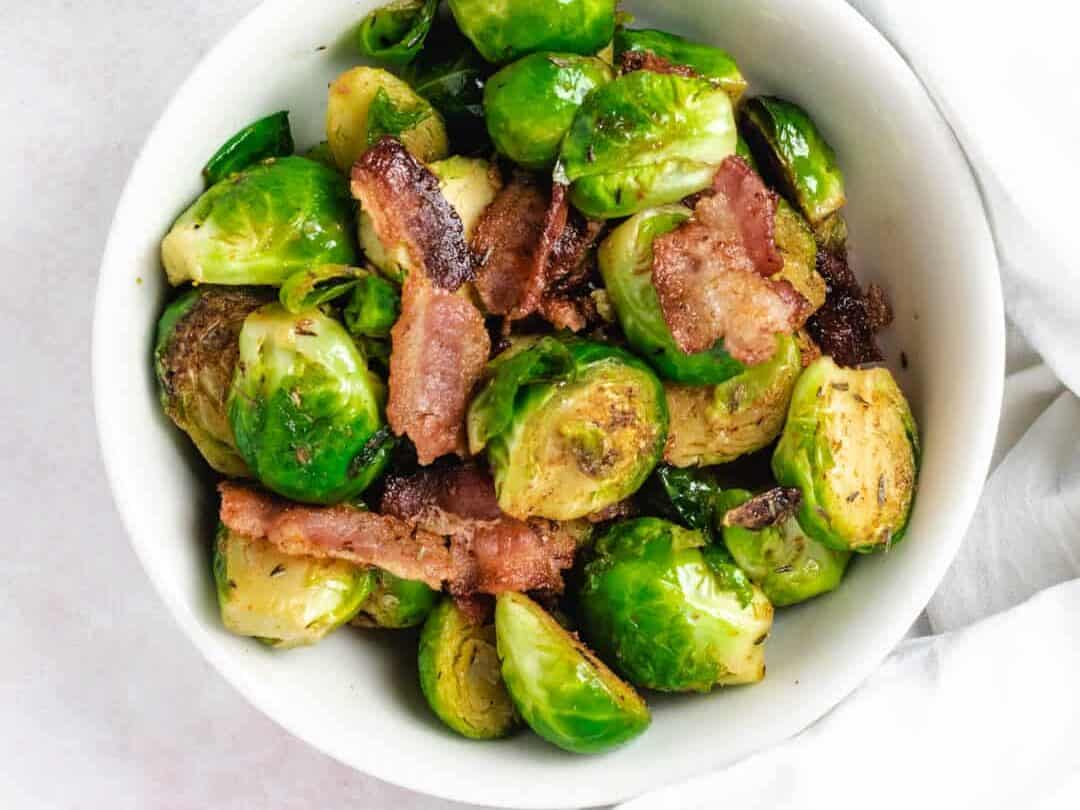 white bowl of brussels sprouts with bacon.