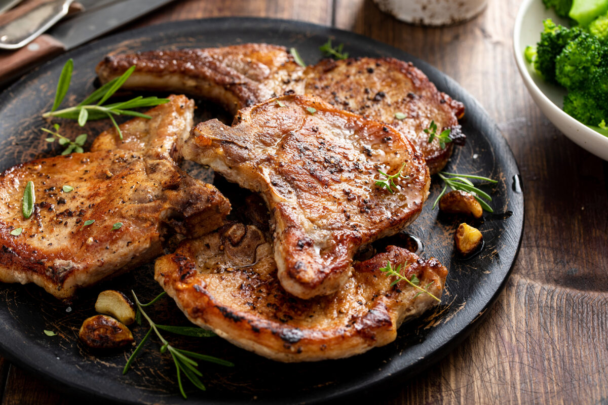 delicious pork chops on a black plate.