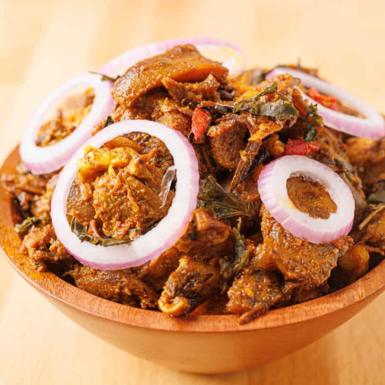 Isiewu spicy goat head on a brown bowl with sliced onions on top