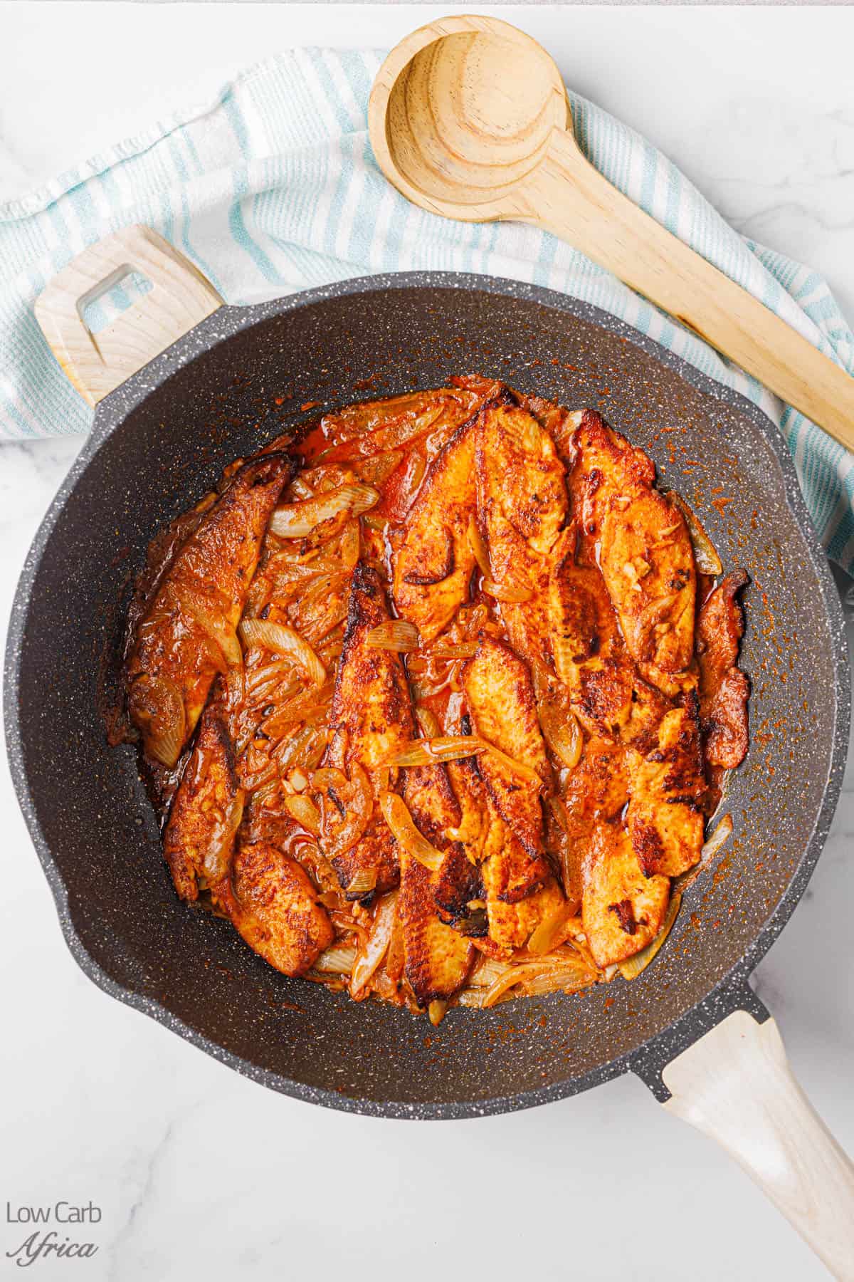 Yassa Fish on a pot with a wooden spoon